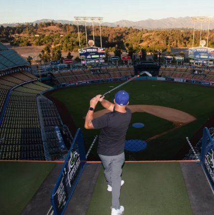 Man hitting golf ball over a baseball field